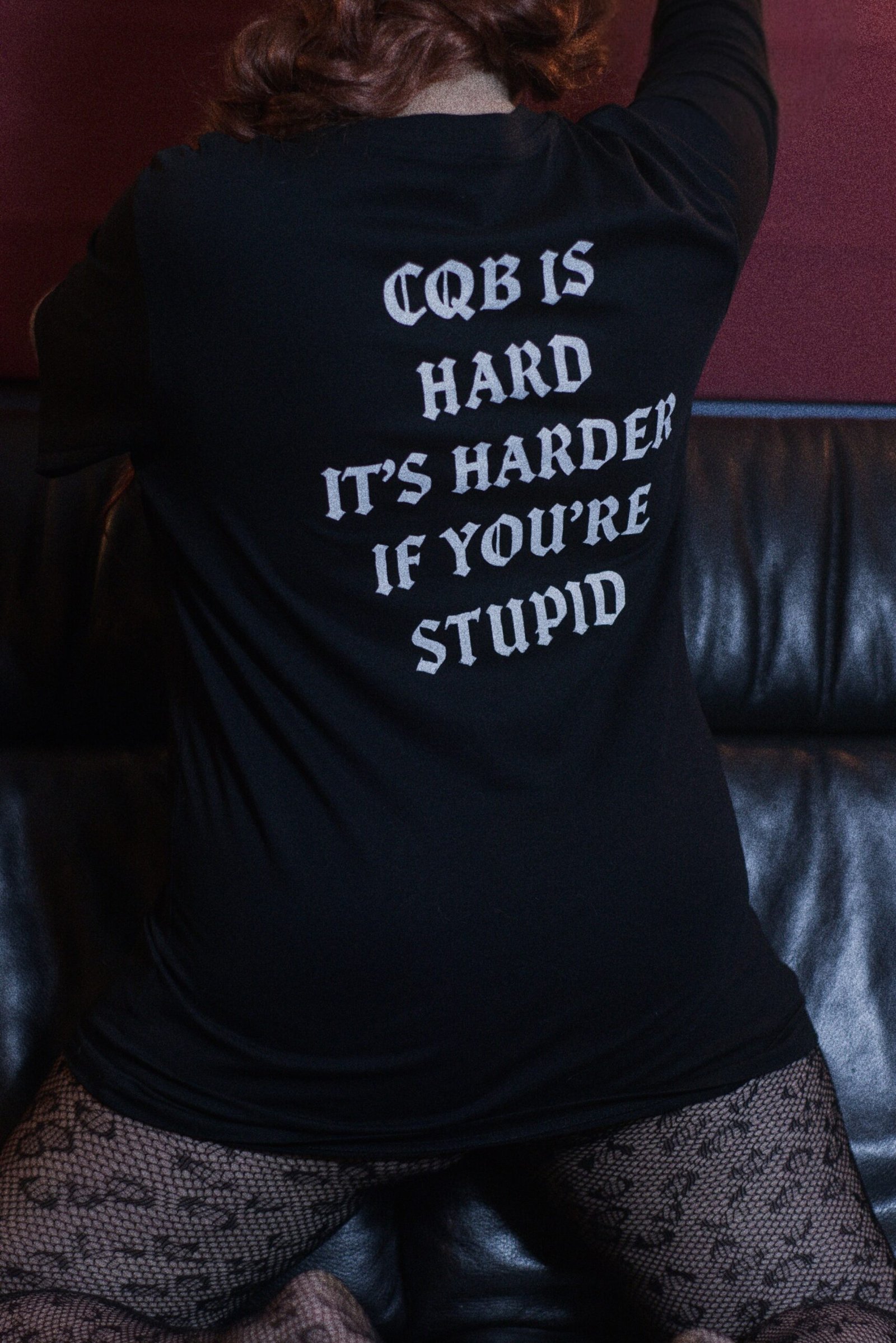 Zweites weibliches Model zeigt die Rückansicht des TIER1ONE Shirts mit dem Aufdruck "CQB is hard".